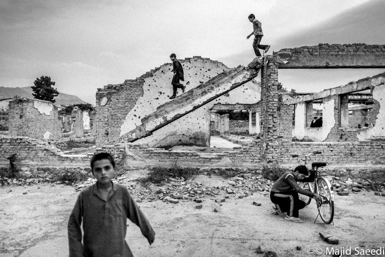 Afghan boys play in the ruins from war in center of Kabul