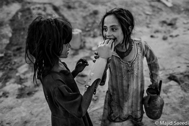 Two Afghan girls play with an artificial hand, south of Kabul